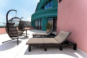 A rooftop terrace with a hanging chair, a lounge chair, and a potted plant. - Spatium Medical & Wellness Hotel (Odesa)