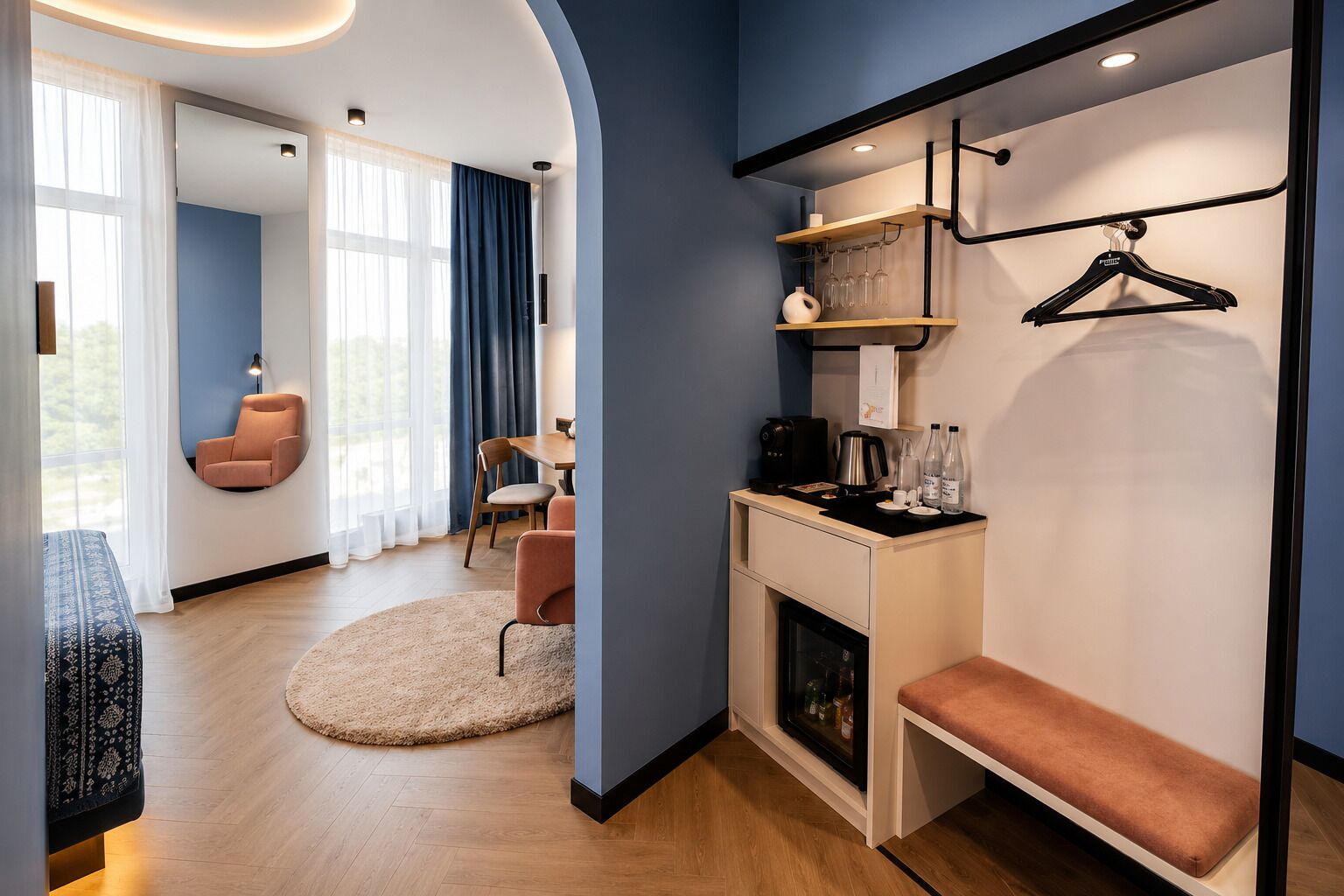 Habitación de hotel moderna con zona de estar, estación de café y armario con espacio para colgar.