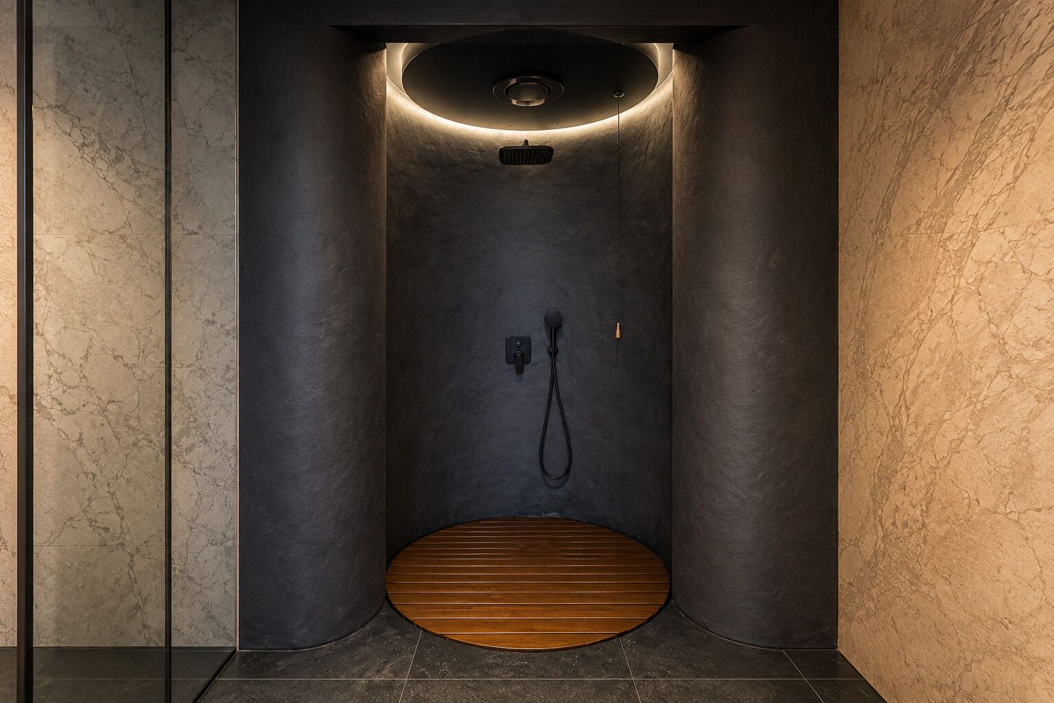 A modern, enclosed shower area with a wooden floor, a handheld showerhead, and a control panel.