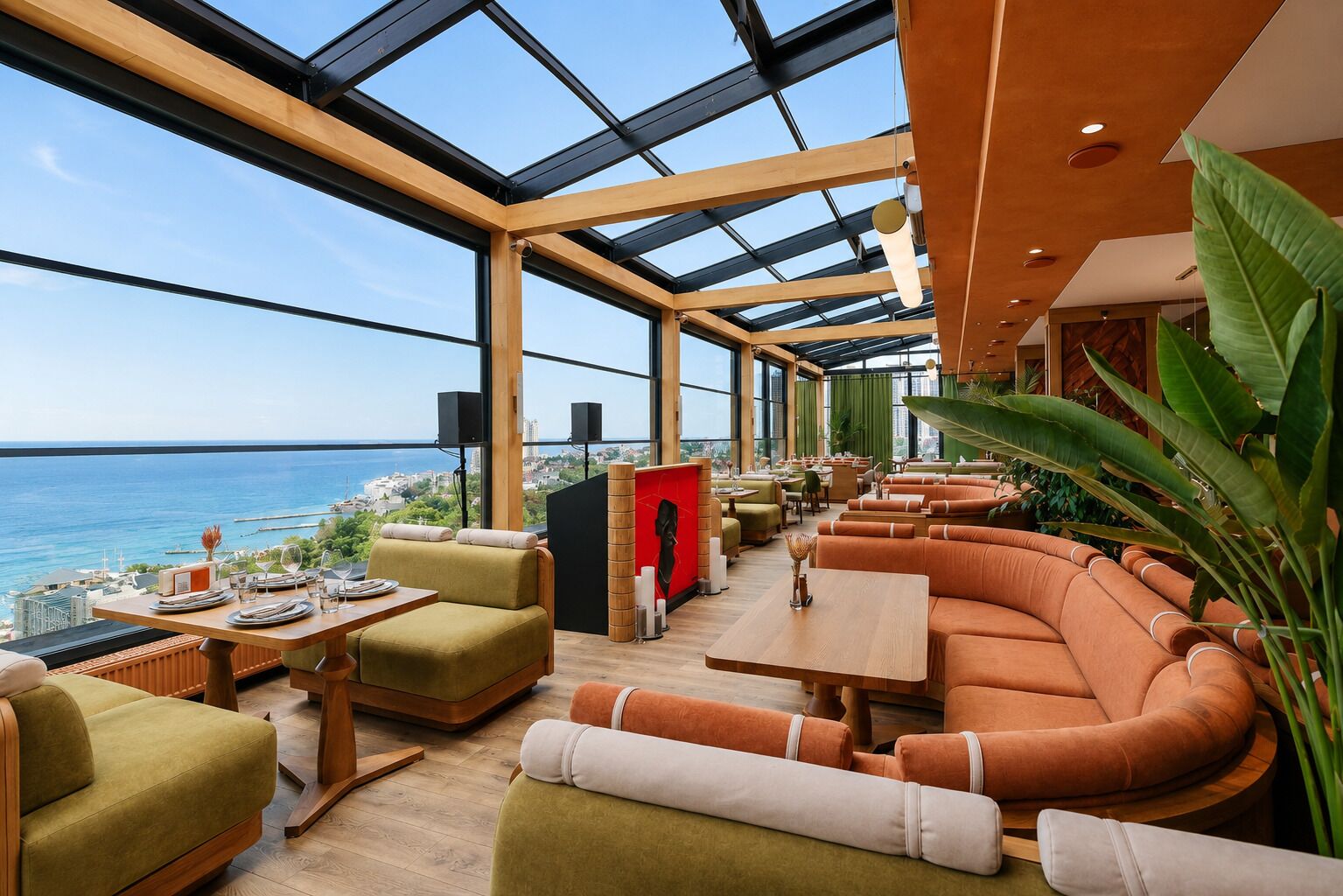 Un interior moderno con techo de vidrio, zona de estar y vistas al mar.