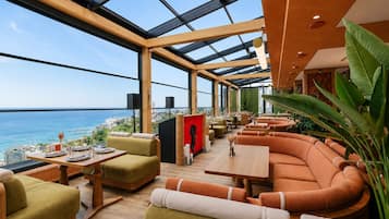 Un interior moderno con techo de vidrio, zona de estar y vistas al mar.