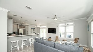 A modern kitchen with white cabinetry, a stainless steel refrigerator, and a bar area with stools. - NAUTICAL NEST - 3-bedroom canal front tranquil home on Summerland Key with AC (Summerland Key)