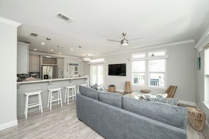 A modern kitchen with white cabinetry, a stainless steel refrigerator, and a bar area with stools. - NAUTICAL NEST - 3-bedroom canal front tranquil home on Summerland Key with AC (Summerland Key)