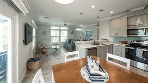 A modern kitchen with a central island, built-in appliances, and a dining area with a wooden table and chairs. - NAUTICAL NEST - 3-bedroom canal front tranquil home on Summerland Key with AC (Summerland Key)