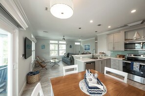 A modern kitchen with a central island, built-in appliances, and a dining area with a wooden table and chairs. - NAUTICAL NEST - 3-bedroom canal front tranquil home on Summerland Key with AC (Summerland Key)