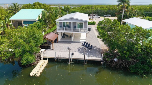 A waterfront property with a dock, a covered patio, and a building with a balcony. - NAUTICAL NEST - 3-bedroom canal front tranquil home on Summerland Key with AC (Summerland Key)