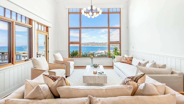 Un salon spacieux avec de grandes fenêtres, une table basse en bois et une vue sur la mer.