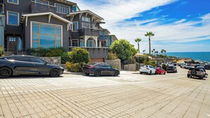 Un immeuble à plusieurs étages doté d’un parking, offrant une vue sur la plage et surplombant un ciel dégagé.