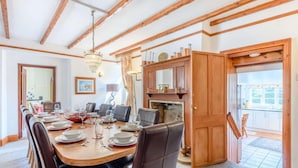 Un comedor con una mesa de madera dispuesta para seis personas, un candelabro y una chimenea.