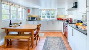Una cocina con armarios blancos, una mesa de madera y una estufa roja.