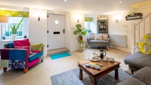 A living room with a sofa, coffee table, and a door. - 3 Bed in Bridport (oc-dc080) (Charmouth)