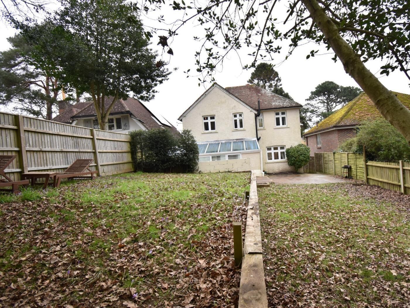 A residential property with a house, a wooden fence, and a garden with fallen leaves.
