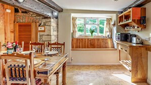 Una cocina rústica con muebles de madera, pared de piedra y ventana con vistas al verdor.