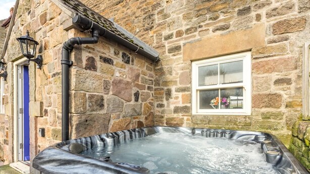 Un bâtiment en pierre avec un jacuzzi en premier plan.