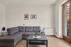 Un soggiorno moderno con un divano ad angolo grigio, un tavolino nero con una pianta e due opere d'arte appese al muro.