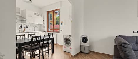 A compact living space with a dining area, kitchen, and a washing machine.