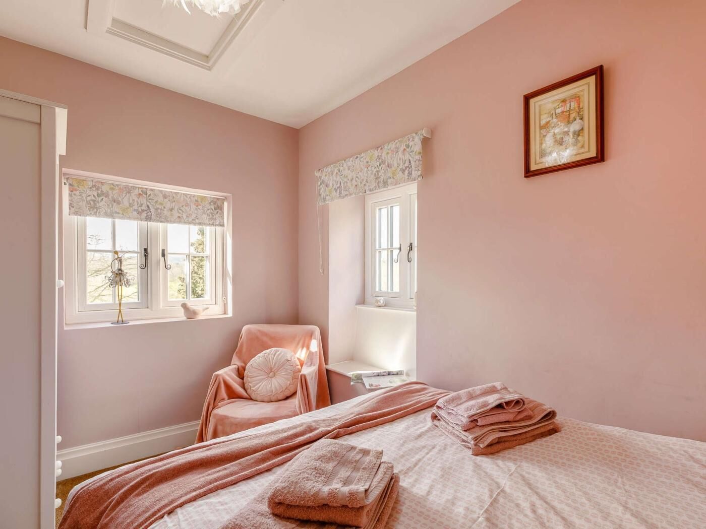 Une chambre à coucher avec un lit, une chaise, une fenêtre avec un rideau, un tableau au mur et une porte.