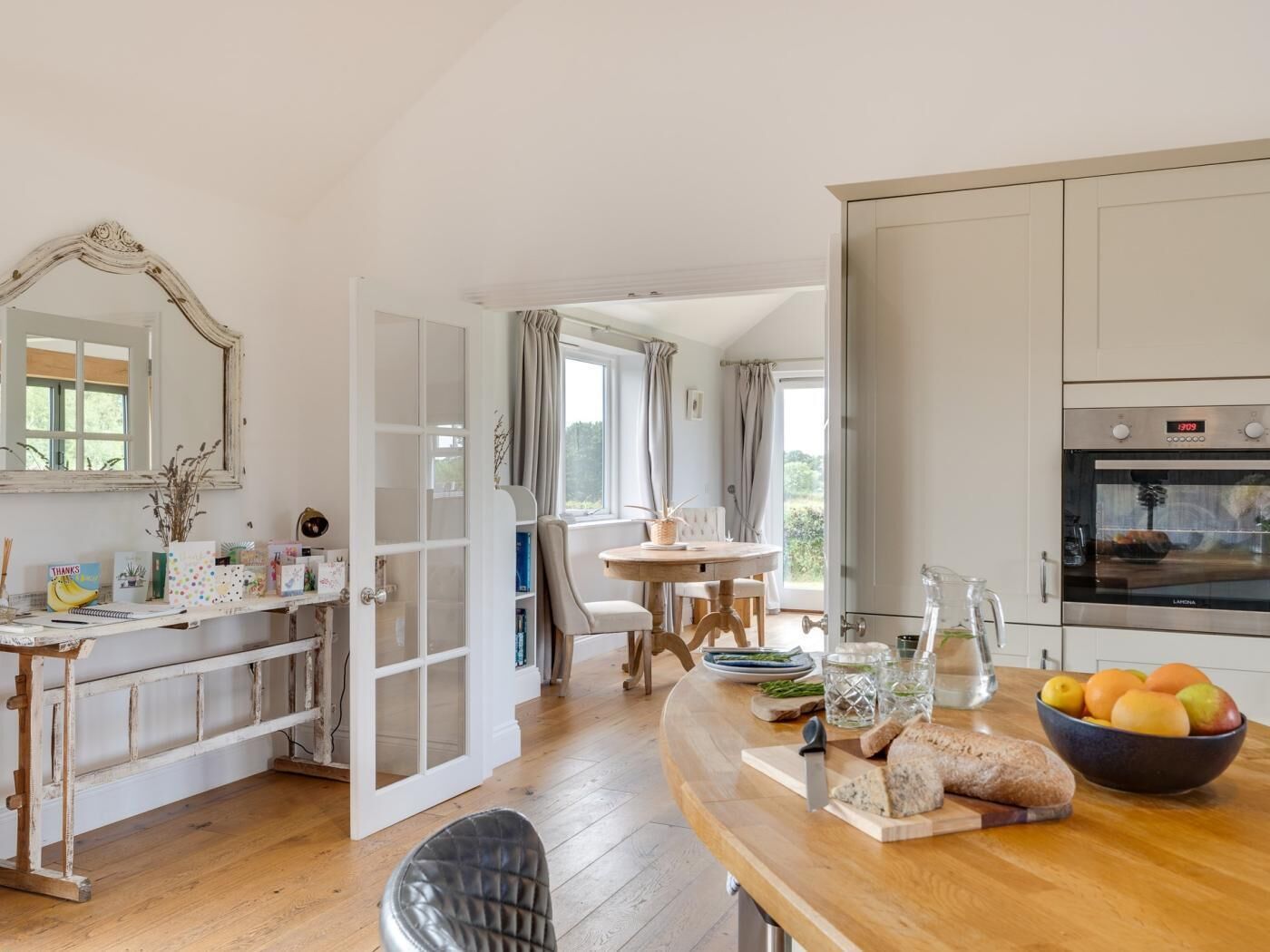 A kitchen with a wooden countertop, a dining table, and a view of the outdoors.