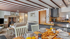 Eine moderne Küche mit Kochinsel, ein Essbereich mit Frühstücksangebot und ein gemütliches Wohnzimmer mit Kamin.