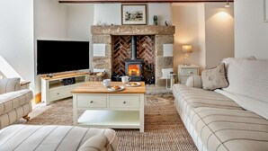 Ein gemütliches Wohnzimmer mit Kamin, Fernseher, Sofa und Couchtisch.