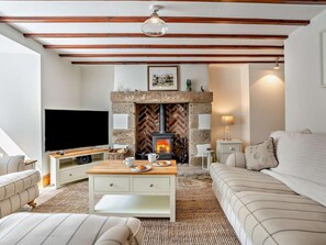 Ein gemütliches Wohnzimmer mit Kamin, Fernseher, Sofa und Couchtisch.