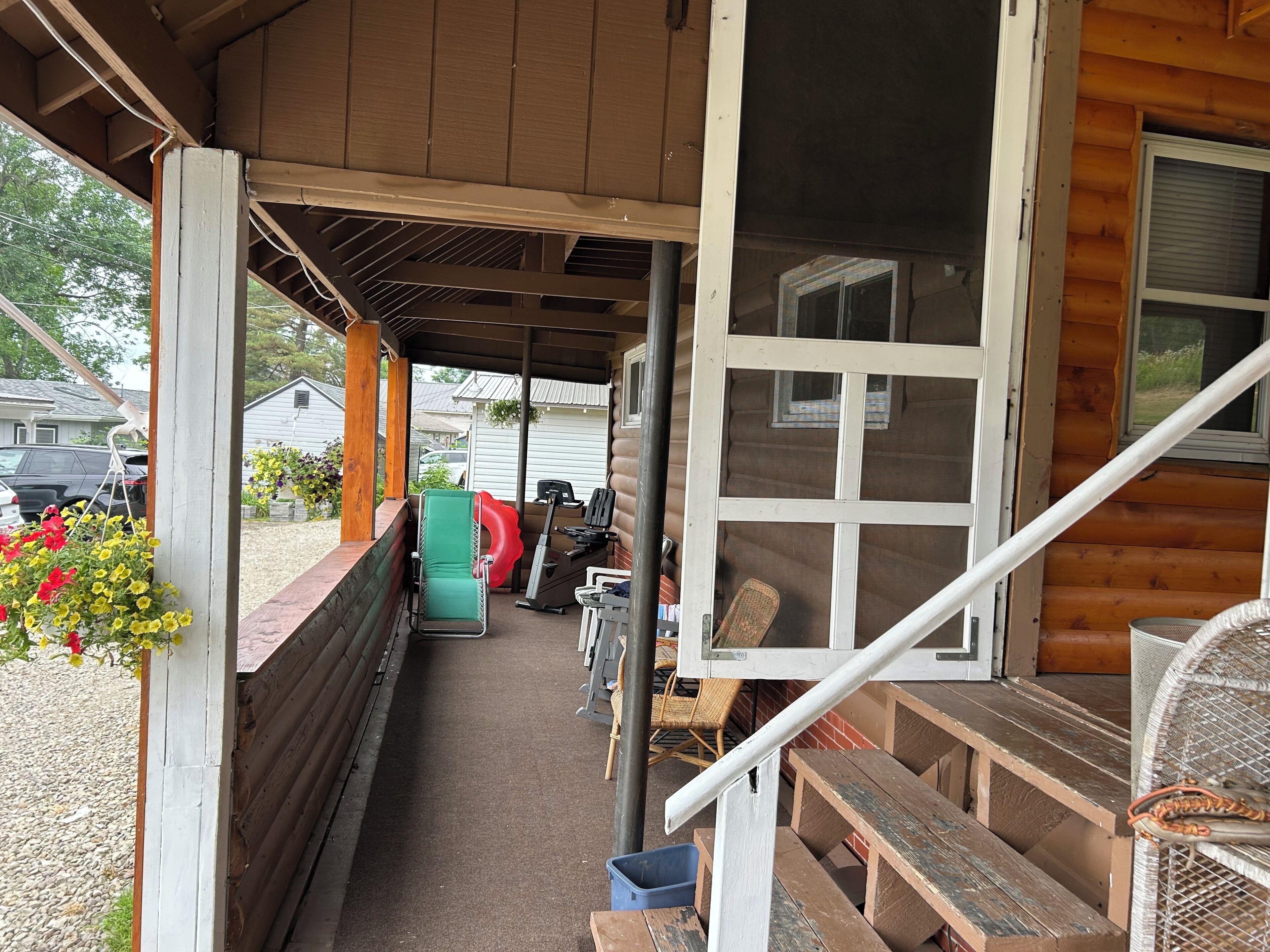 A covered porch with a bench, a table, a fan, and a window.