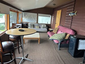 A cozy room with a round table, a sofa, a television, and a window.