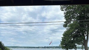 A lakeside view with a dock, boats, a flag, and a vehicle.