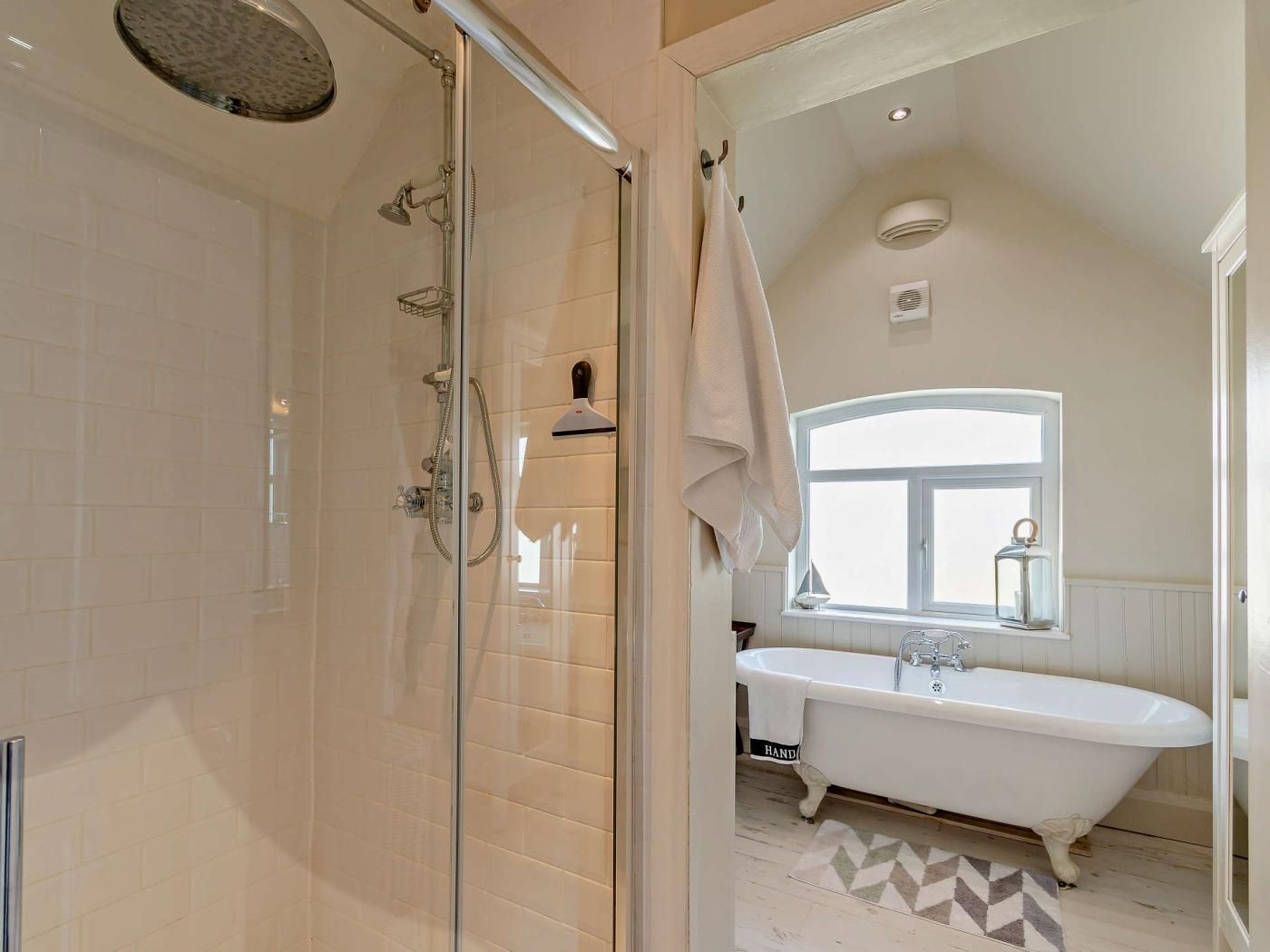 Un bagno con cabina doccia in vetro, una vasca freestanding e una finestra che lascia entrare luce naturale.