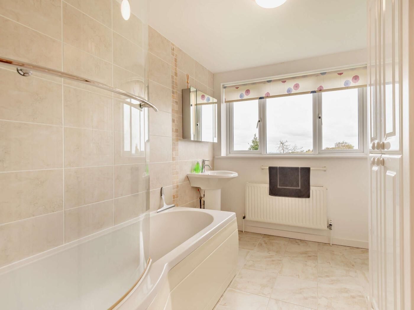 A modern bathroom with a bathtub, a sink, a mirror, and a window with a view.