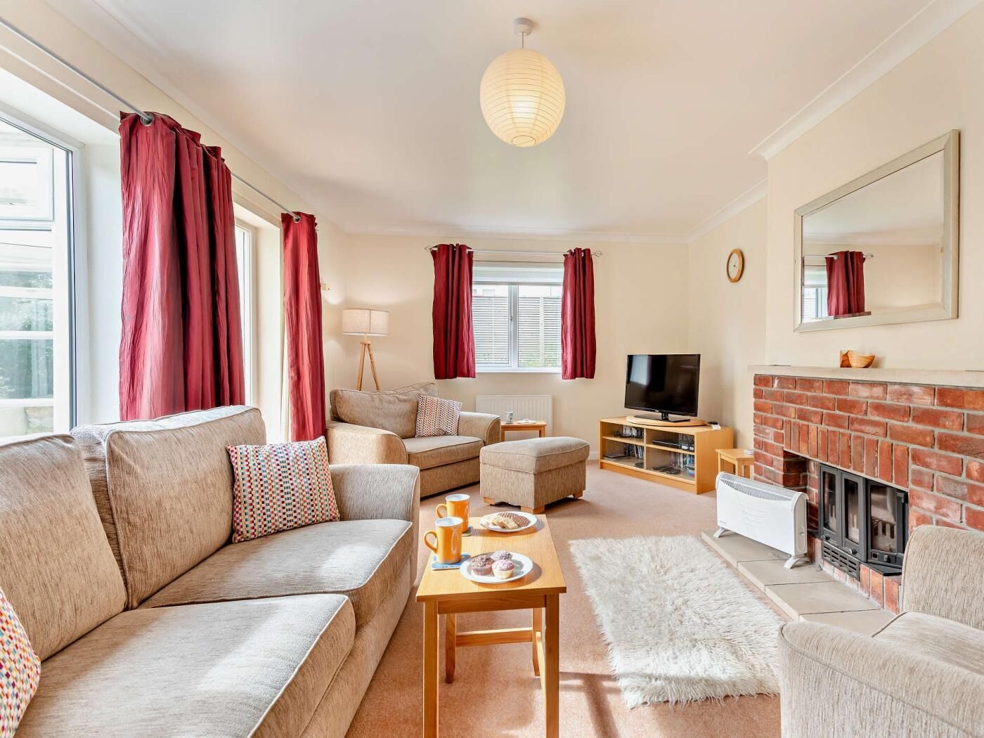 A living room with a sofa, armchair, coffee table, TV, fireplace, and a lamp.