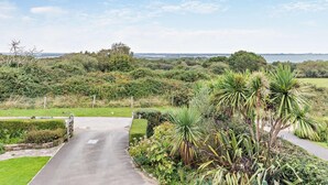 Ein gepflasterter Weg schlängelt sich durch einen üppigen Garten mit verschiedenen Pflanzen und bietet einen Blick auf das Meer in der Ferne.