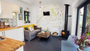 A modern living space with a kitchen, a sofa, a coffee table, a fireplace, and a large window. - 1 Bed in Abergavenny (oc-75206) (Gilwern)