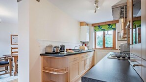 Una cocina con armarios de madera, encimera de granito y ventana con vistas a la vegetación.