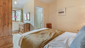 Un dormitorio con cama, armario de madera, cómoda y ventana con flores.