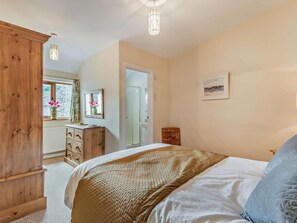 A bedroom with a bed, wooden wardrobe, dresser, and a window with flowers. - 3 Bed in Keswick (oc-sz153) (Braithwaite)