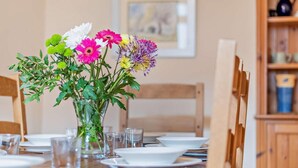 Una mesa de comedor dispuesta con platos, vasos y un florero con flores.