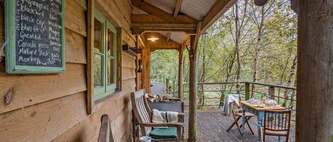 A wooden cabin with a covered porch, a chalkboard menu listing various birds, and a dining area with outdoor seating.