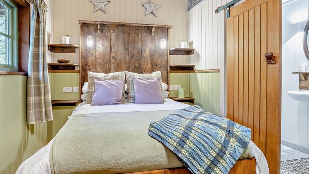 A bedroom with a wooden bed, two bedside tables, a headboard, and a star decoration on the wall.