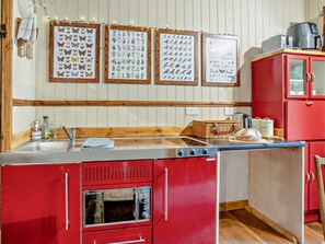 Een keuken met een rode koelkast, een houten aanrecht en ingelijste foto's aan de muur.