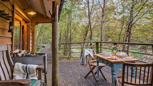A wooden deck with a table and chairs, surrounded by trees.