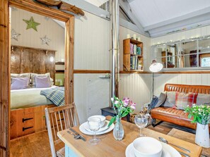 Une pièce confortable avec un lit, une table en bois dressée pour le repas, un canapé et une bibliothèque.
