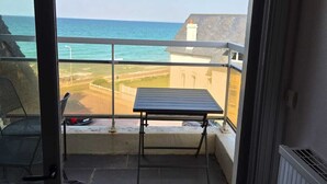 En balkon med et bord og stole, der kigger ud over kysten.