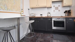 Una cocina moderna con un mapa, un taburete de bar, lavavajillas, horno y salpicadero de azulejos.