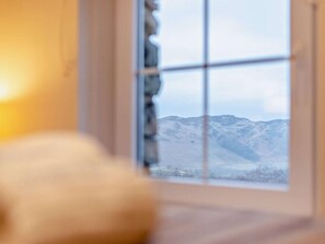 Ein Zimmer mit Fensterblick auf eine gebirgige Landschaft.