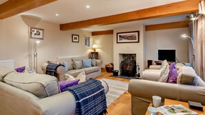 A living room with a fireplace, two sofas, a coffee table, and a television. - 3 Bed in Penrith (oc-sz247) (Dockray)