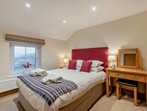 Ein Schlafzimmer mit Bett, Nachttisch, Lampe und Blick ins Freie.