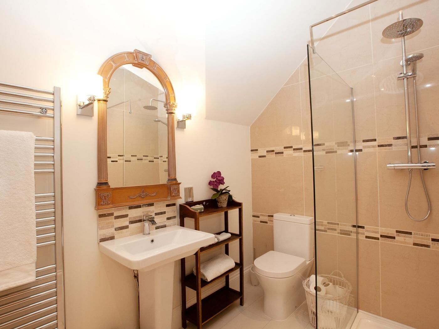 Een badkamer met een douche met glazen wand, een wastafel met spiegel en een toilet.