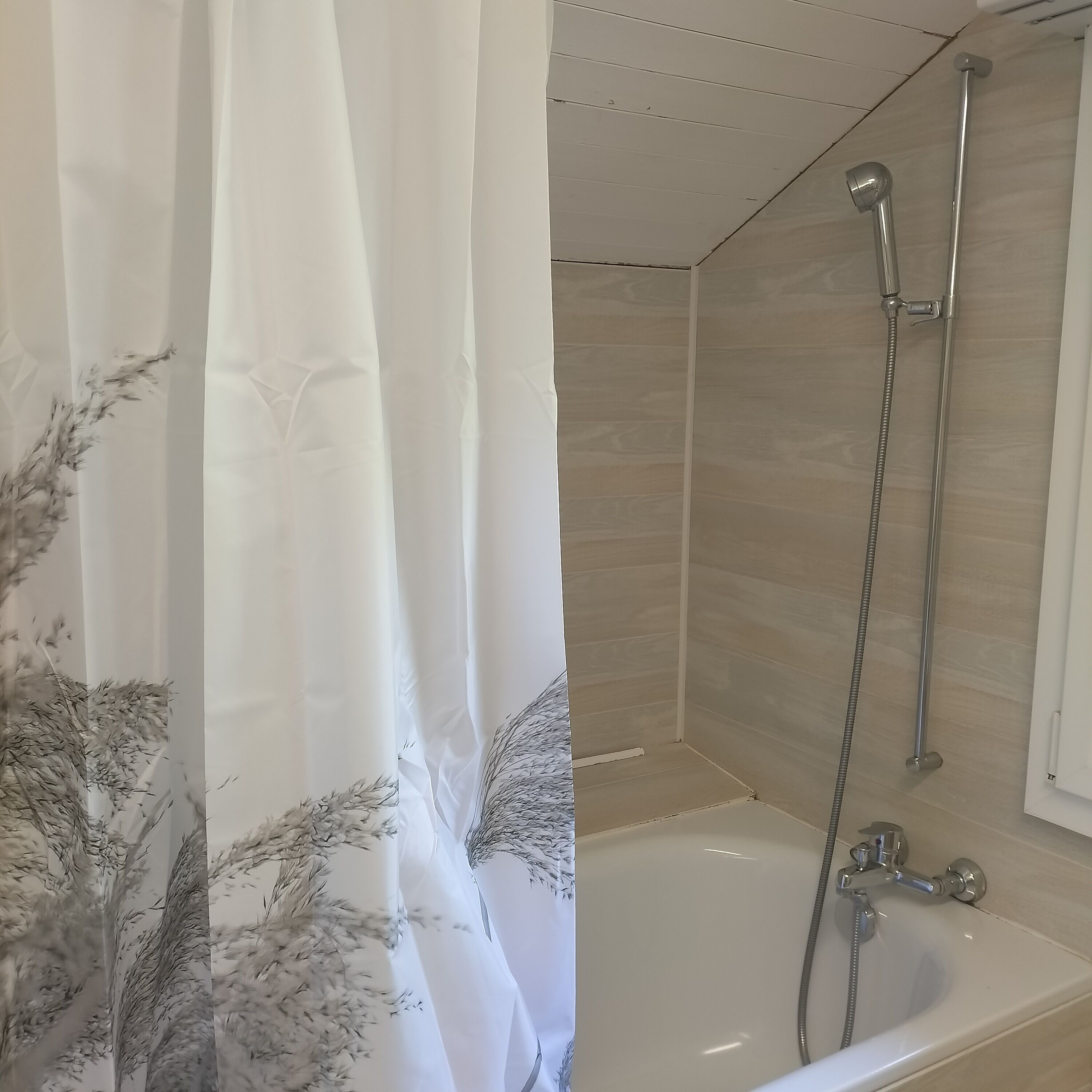 Ein Badezimmer mit Dusche, Badewanne und einem Vorhang mit Blumenmuster.