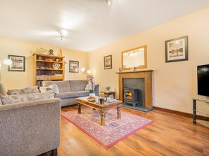 Ein Wohnzimmer mit Sofa, Couchtisch, Kamin und Fernseher.